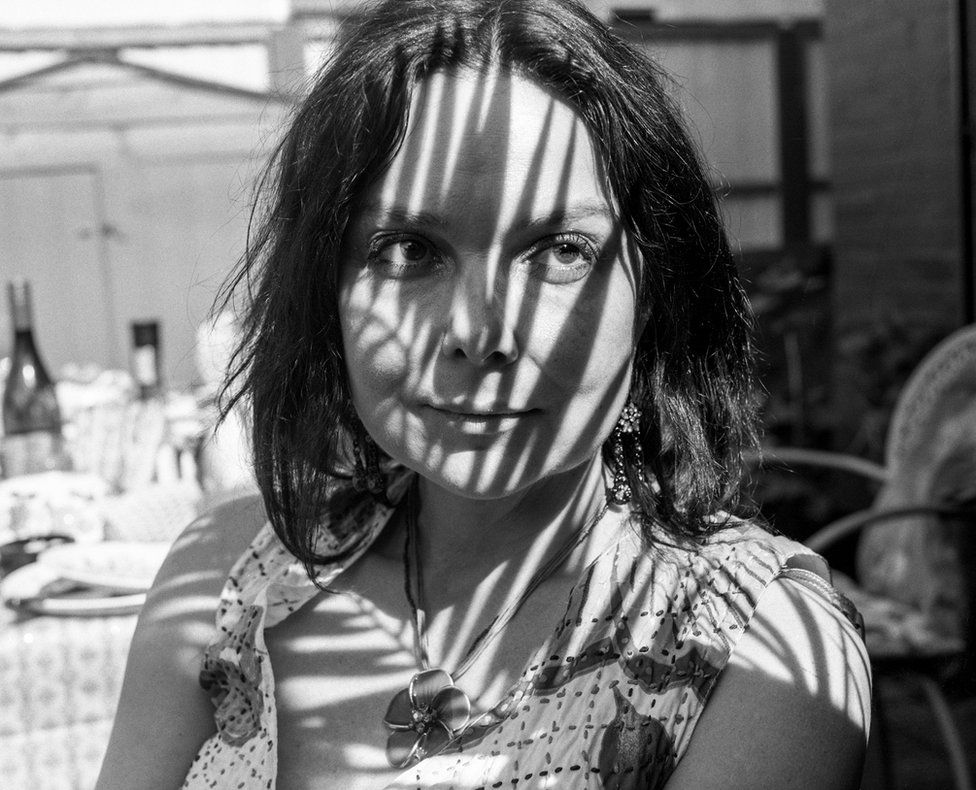 A portrait of a woman with light and shadows cast on her face