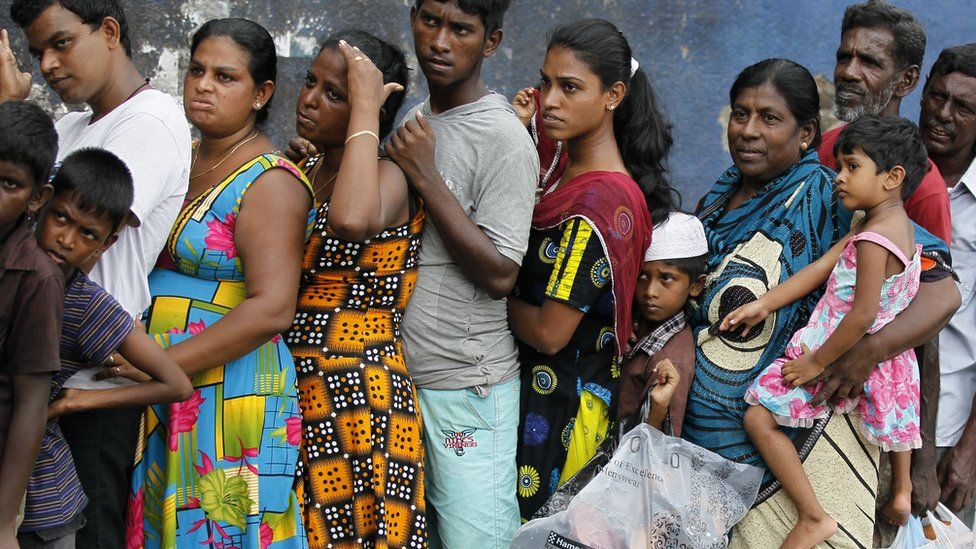 Sri Lankan flood victims line up to receive relief materials in a flood affected area near Colombo