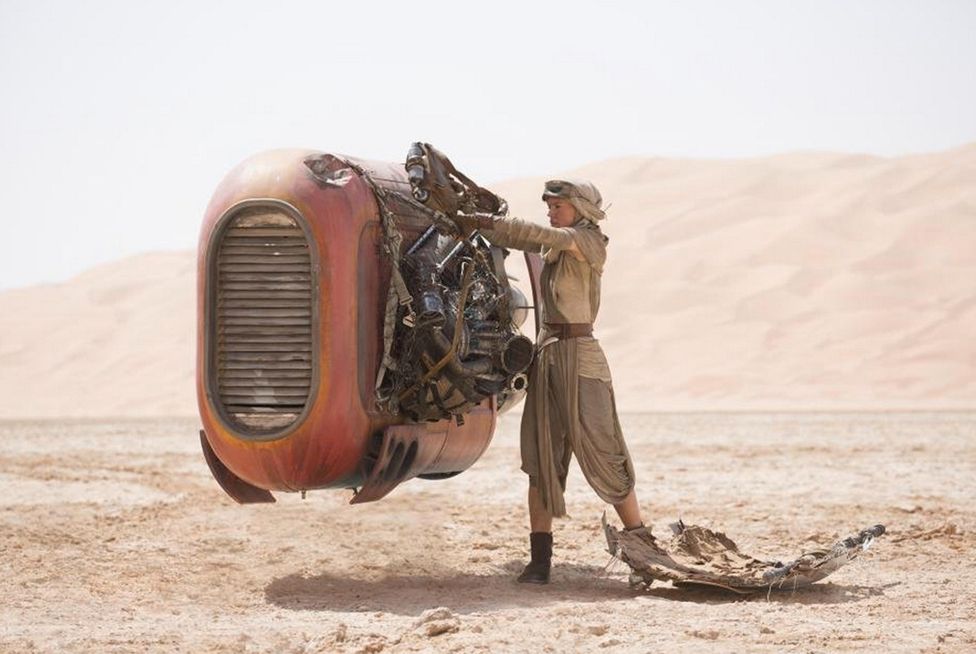 Rey (Daisy Ridley) fixes an old piece of machinery on her desert planet