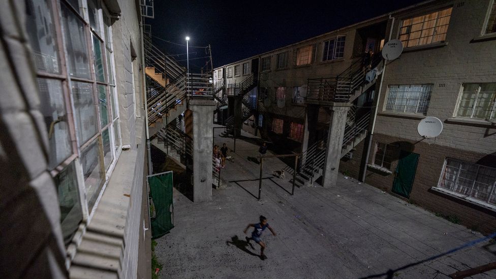 Мальчик бежит между квартирами в Маненберге, Кейптаун, Южная Африка