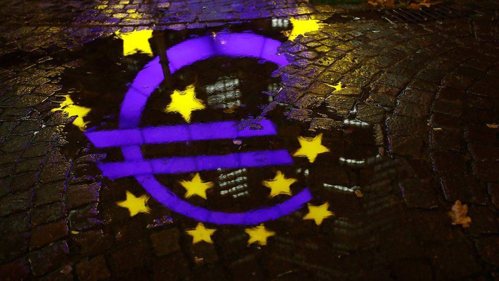 The euro sign in front of the former headquarters of the European Central Bank (ECB) is reflected in a puddle during heavy rain in Frankfurt