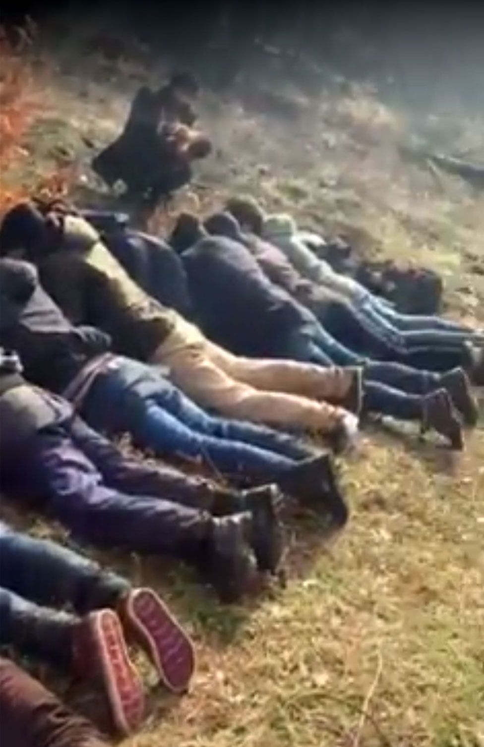 Migrants forced to lie on the ground