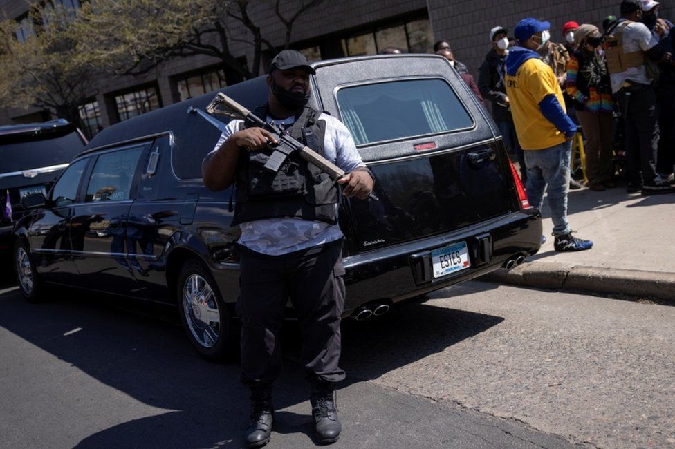 A member of the Minnesota Freedom Fighters militia guards the car carrying Duante Wright's coffin
