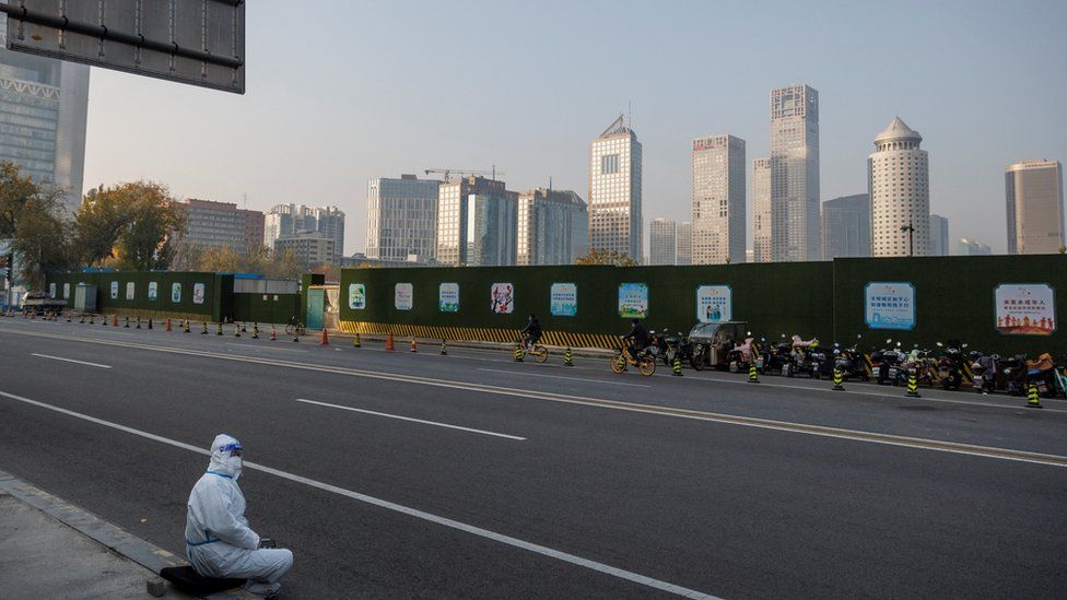 Un trabajador de prevención de epidemias con traje protector se sienta en la acera del Distrito Central de Negocios (CBD) mientras continúan los brotes de la enfermedad coronavirus (COVID-19) en Beijing, el 23 de noviembre de 2022.