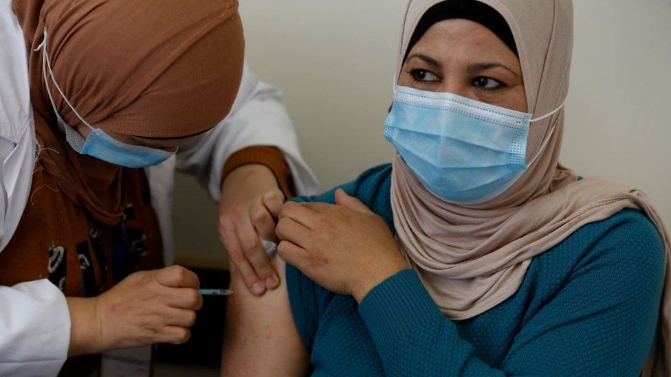A Palestinian healthcare worker administers the Covid-19 vaccine to a patient