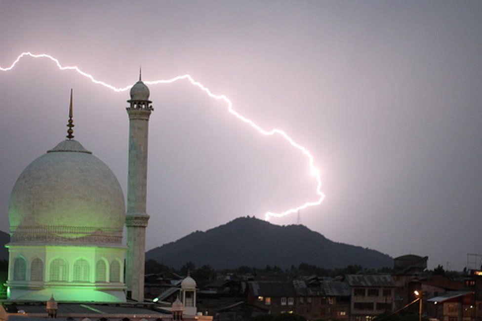 Низкий угол обзора мечети против молнии на холме ночью, Сринагар