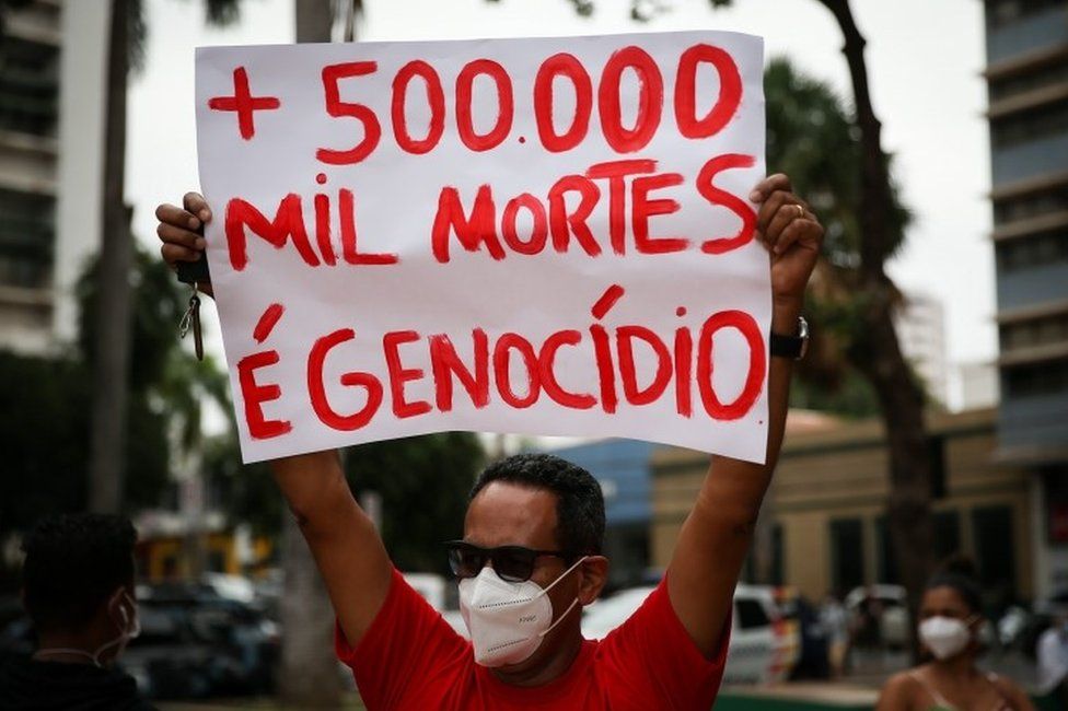 A man holds up a sign protesting against the Covid death toll in Brazil