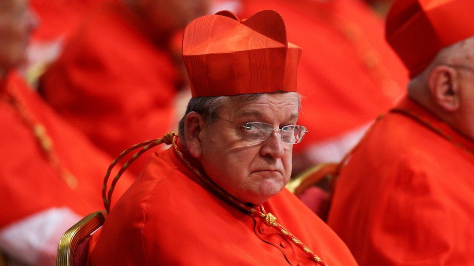 Burke wearing glasses and red vestments