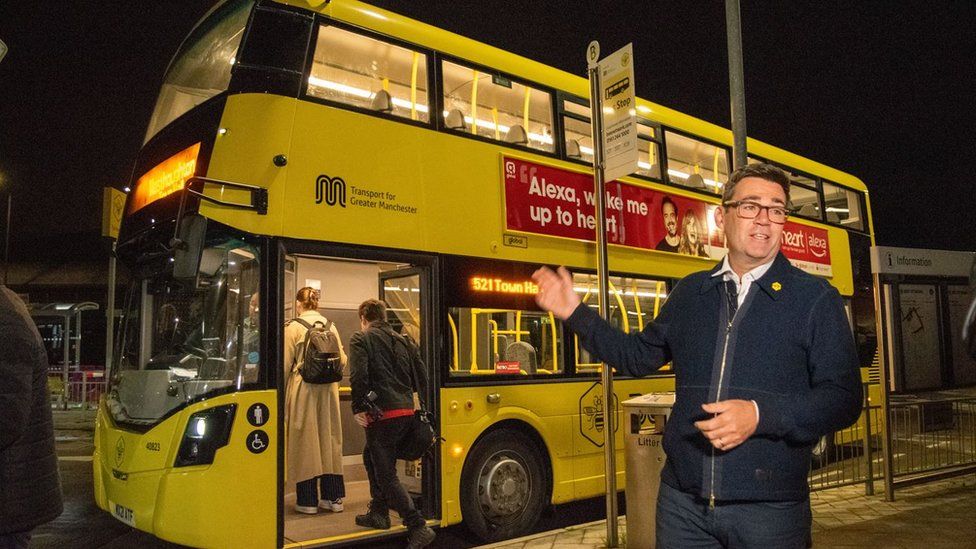 Andy Burnham by a Bee Network buses during the night