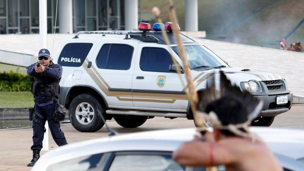 Riot police points his gun at Brazilian Indians during a demonstration against the violation of indigenous people's rights, in Brasilia, Brazil April 25, 2017.