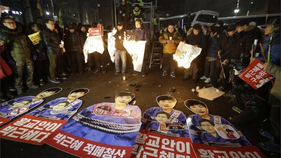 Protesters burn their banners against impeached President Park Geun-hye"s policies during a candle light vigil calling for Park to step down near the presidential house in Seoul, South Korea, on 31 December