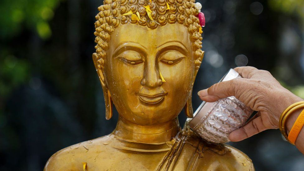 Water being poured onto a sacred statue of Buddha
