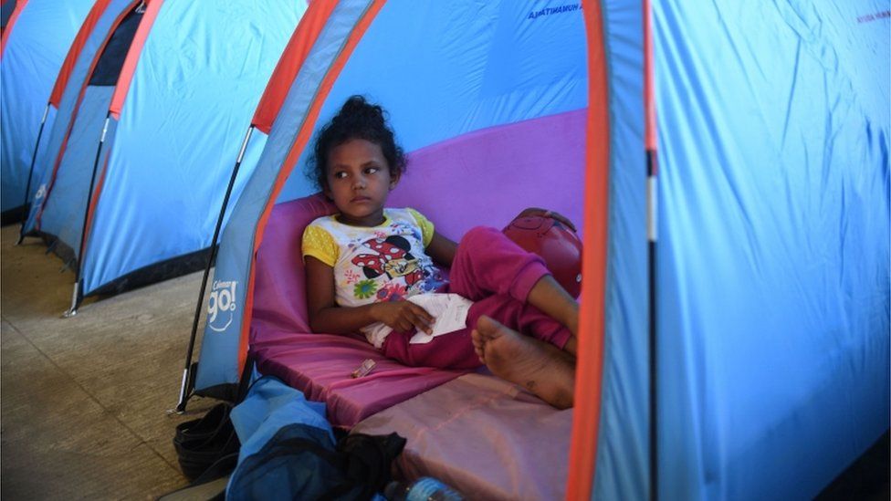 migrant child rests in tent