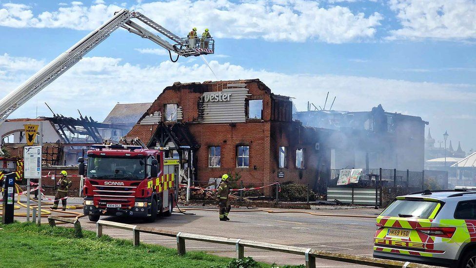 A burnt down Harvester building with fire engine outside