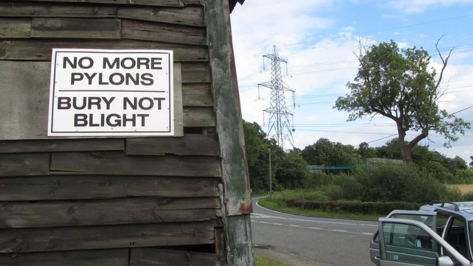 Sign saying "No more pylons, bury not blight" with a pylon in the background