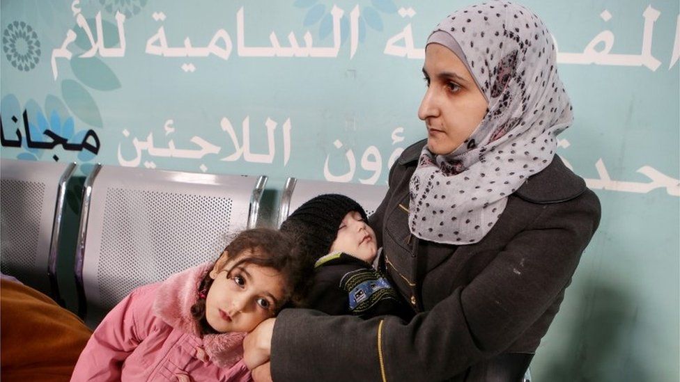 A woman and her children wait to register at the UN Refugee Agency in Jordan