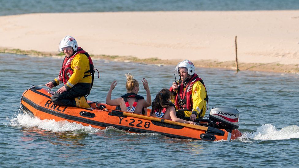 The RNLI and Coast Guard bringing members of the public back from East Beach