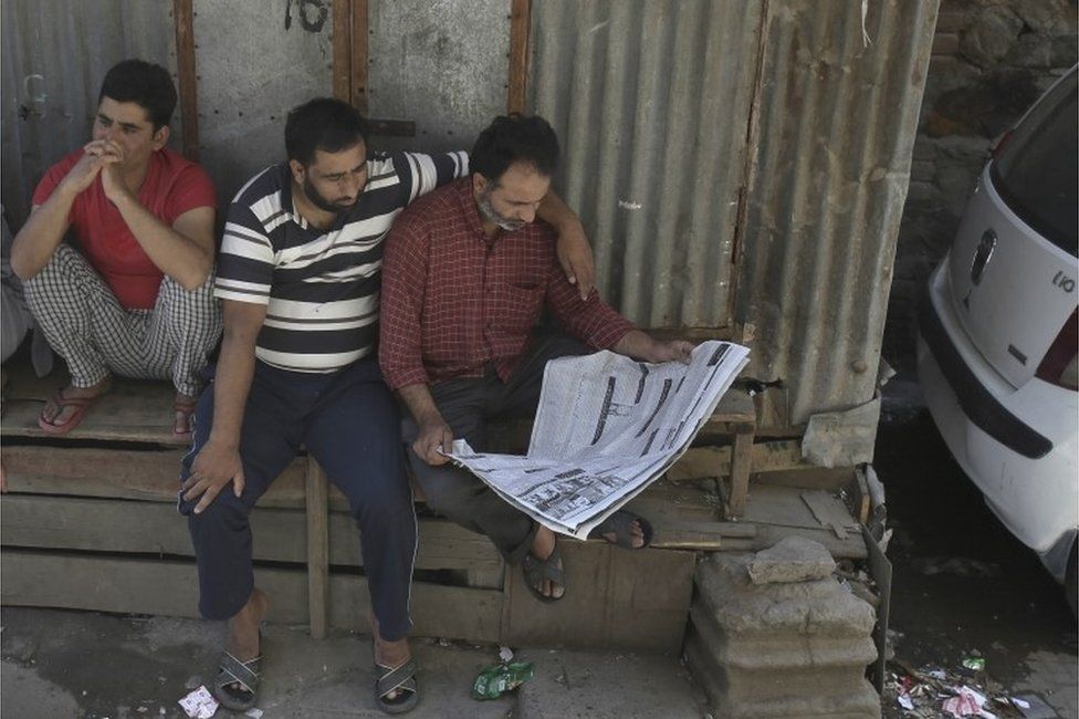 Kashmiri men read the newspaper during a curfew in Srinagar, Indian controlled Kashmir, Thursday, Aug. 18, 2016.