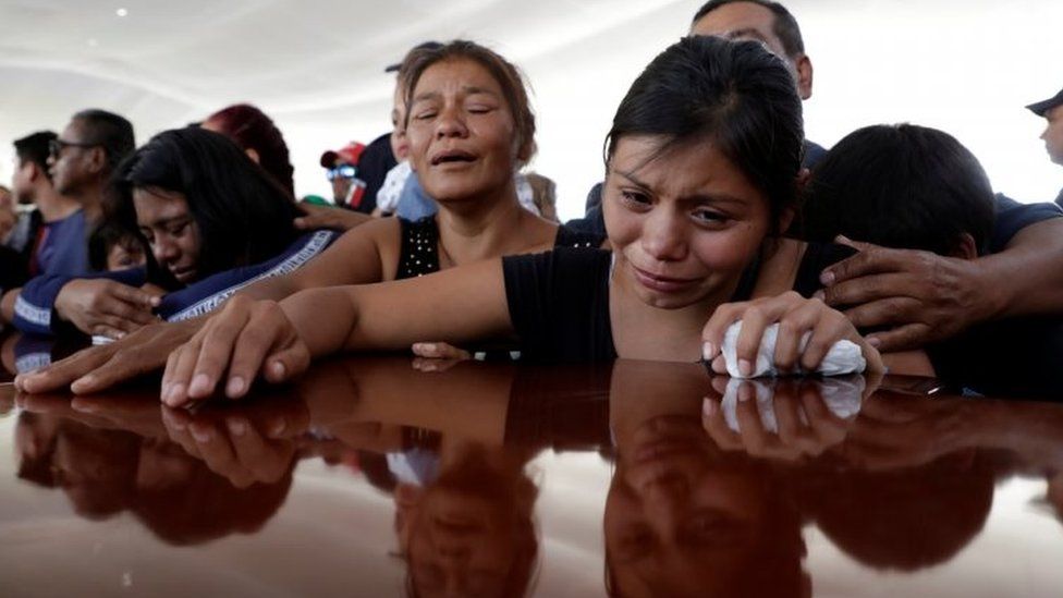 People in Morelia, Michoacán state, grieve near a coffin of one of the police officers killed in the ambush. Photo: 15 October 2019
