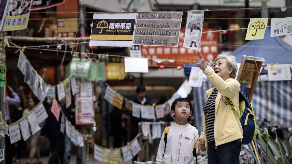 A elderly woman explains to a child the meaning of posters set up by pro-democracy protesters at a protest site in the Causeway Bay district of Hong Kong on November 14, 2014.