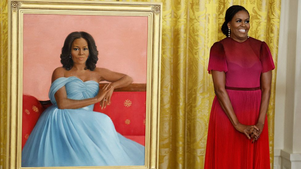 Former US first lady Michelle Obama poses next to her official White House portrait, painted by Sharon Sprung