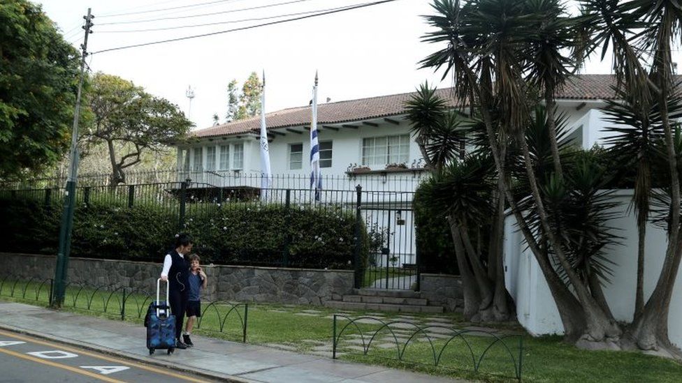 A woman and a child walk outside the residence of the Uruguayan ambassador in Peru