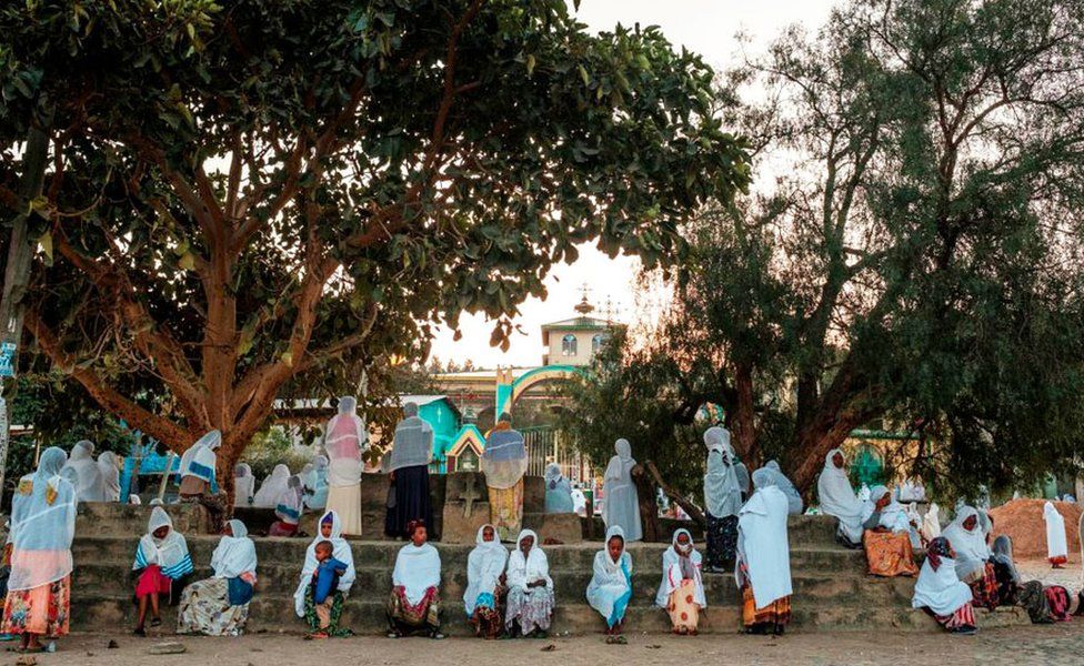 Mostly female worshippers sitting on steps