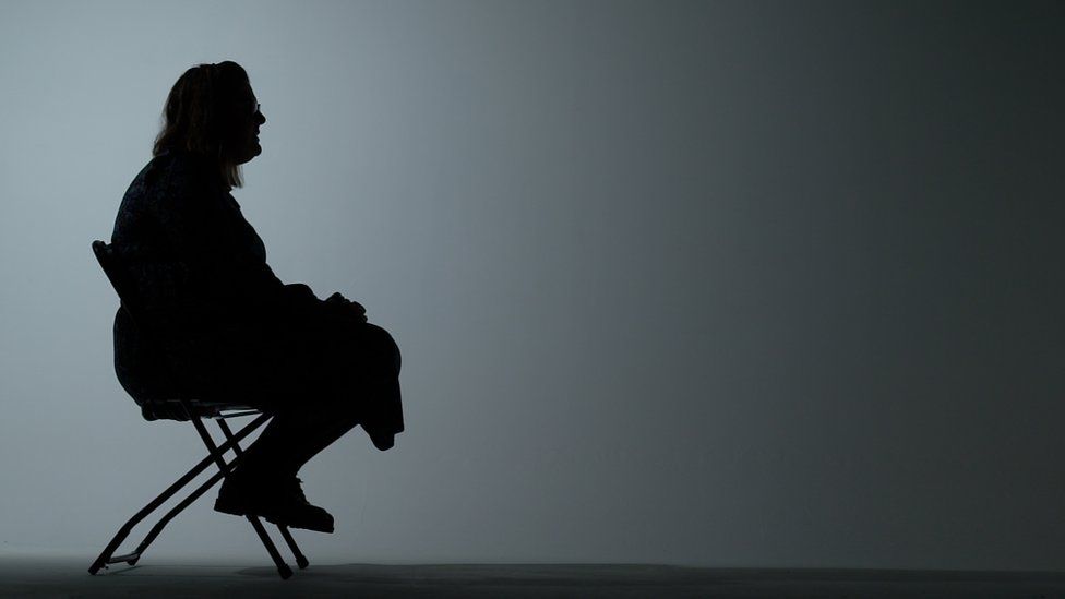 The silhouette of an anonymous case study sitting on a chair