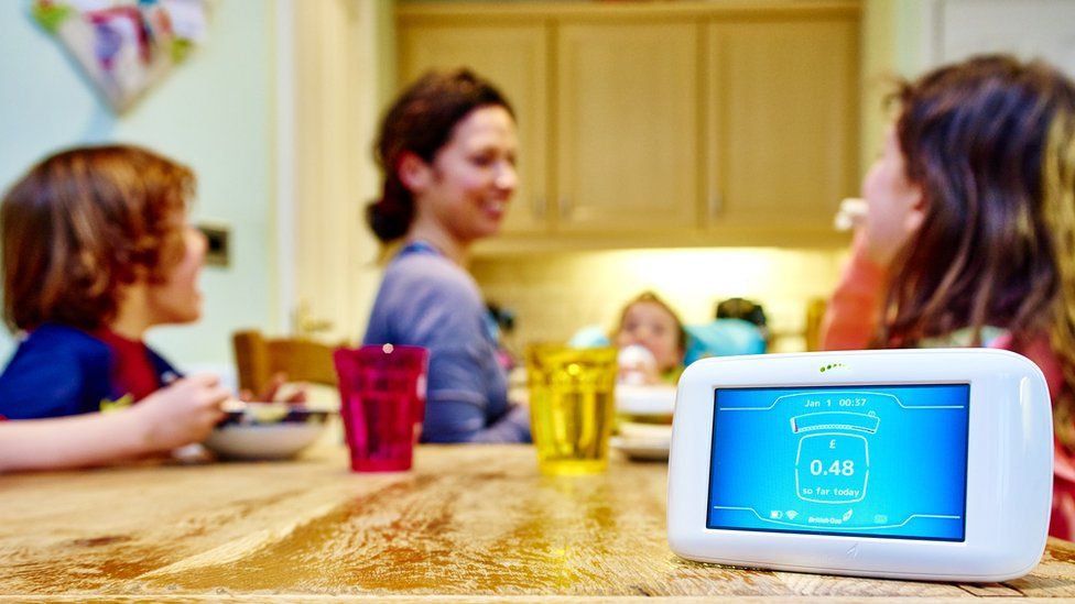 A smart meter with a family in the background