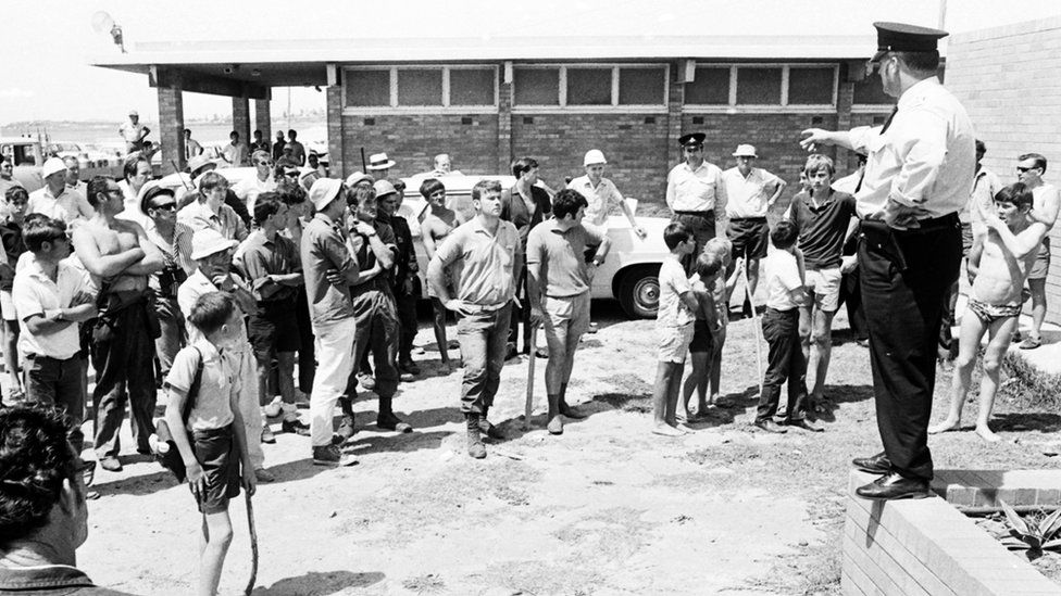 A policeman directs a crowd of officers and volunteers at Fairy Meadow beach