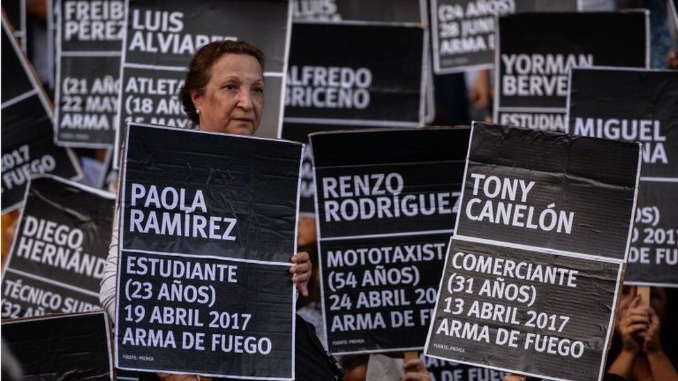 Venezuelan opposition activists take part in a peaceful demonstration carrying black placards with the name of one of the 125 people killed in past protests on each one, in Caracas on August 30, 2017.