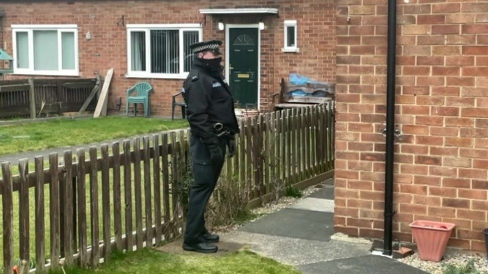 A police officer outside a property in Upper Garth Gardens
