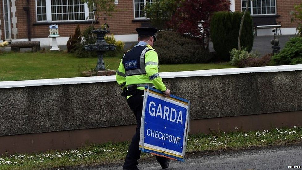 An Irish police officer removes a Garda checkpoint sign at the Armagh and County Louth border between Northern Ireland and Ireland, during a visit by European Union Chief Negotiator for Brexit Michel Barnier