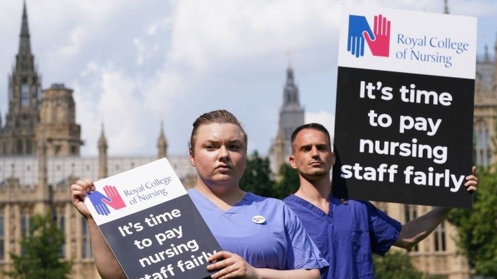Медсестры с плакатами возле Королевского колледжа медсестер (RCN) в Victoria Tower Gardens, Лондон