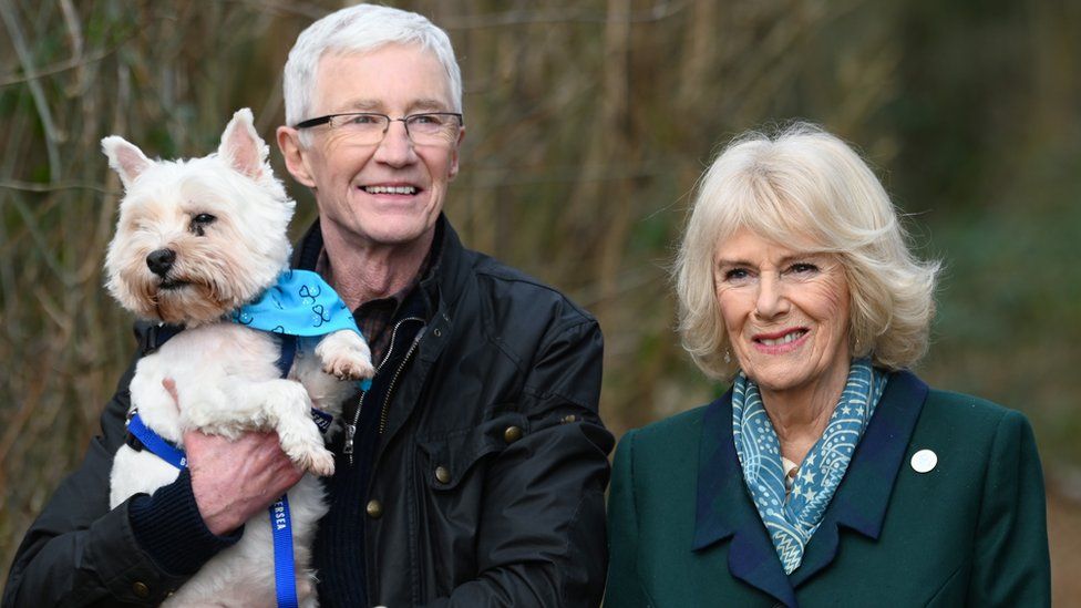 Camilla, Duchess of Cornwall, patron of Battersea Dogs and Cats Home and Battersea Ambassador Paul O'Grady on a brief woodland walk with a rescue dog which is yet to be re-homed, during her visit to Battersea Brand Hatch Centre on February 2, 2022 in Ash, England