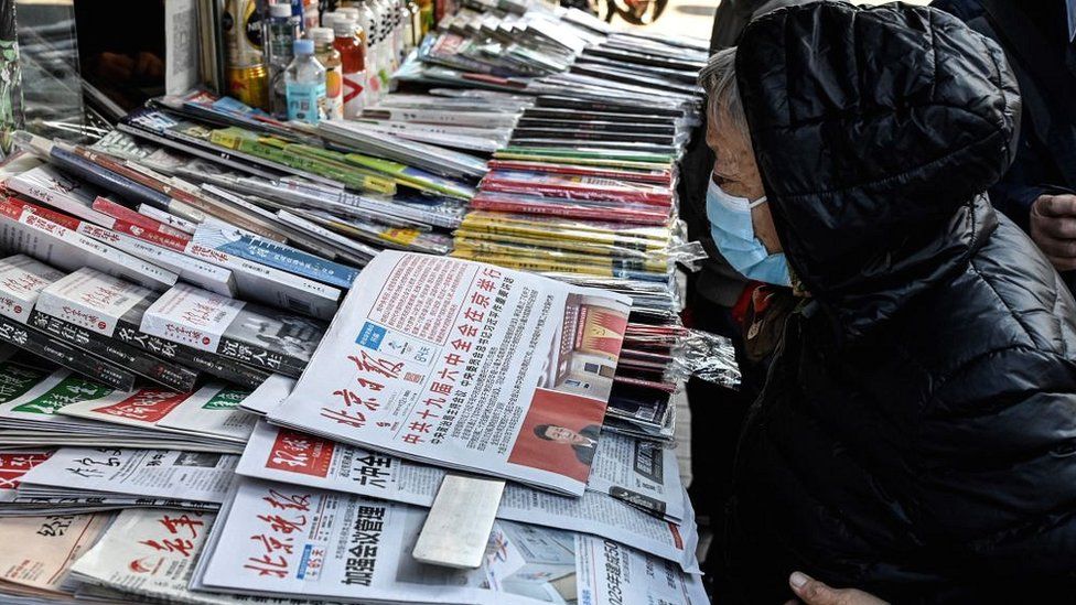 A woman reads a Chinese newspaper covering the Communist Party's sixth plenum meeting at a news stand in Beijing on November 12, 2021