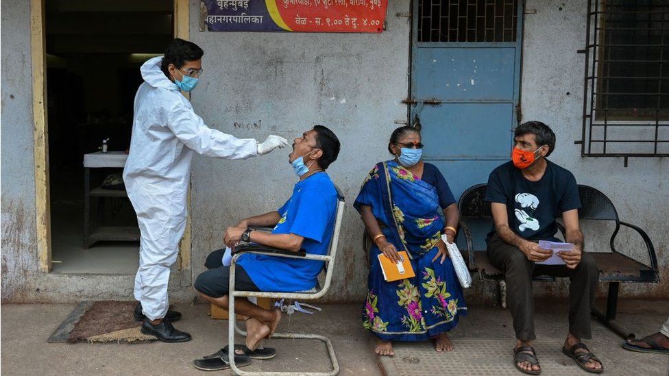 Медицинский работник берет образец мазка у жителя для теста на коронавирус Covid-19 в медицинском центре в трущобах Дхарави в Мумбаи 17 апреля 2021 года.