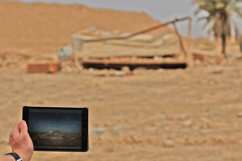 A picture taken on 15 November 2016 shows a tablet with a picture of the ancient ruins of Nimrud before and after their destruction by IS militants