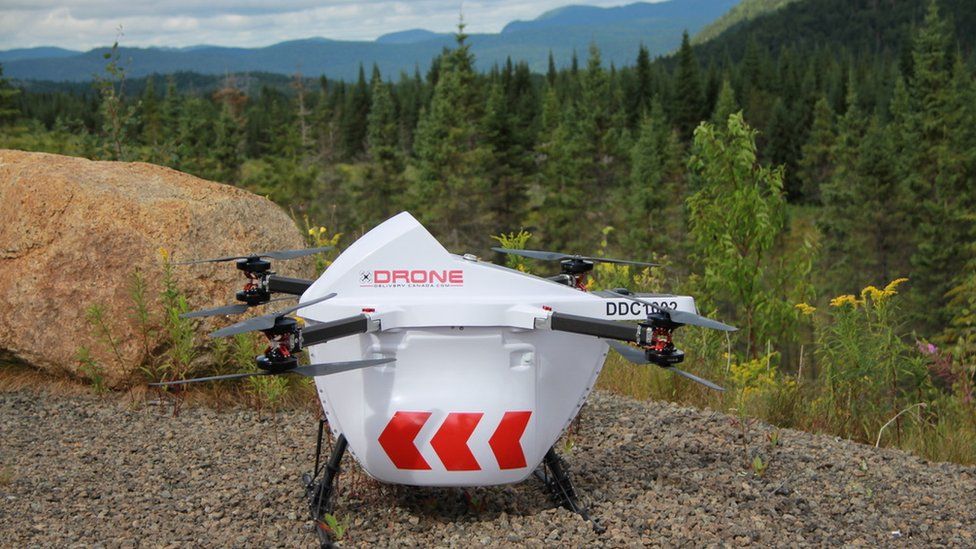Drone sits on ground with green forest behind it