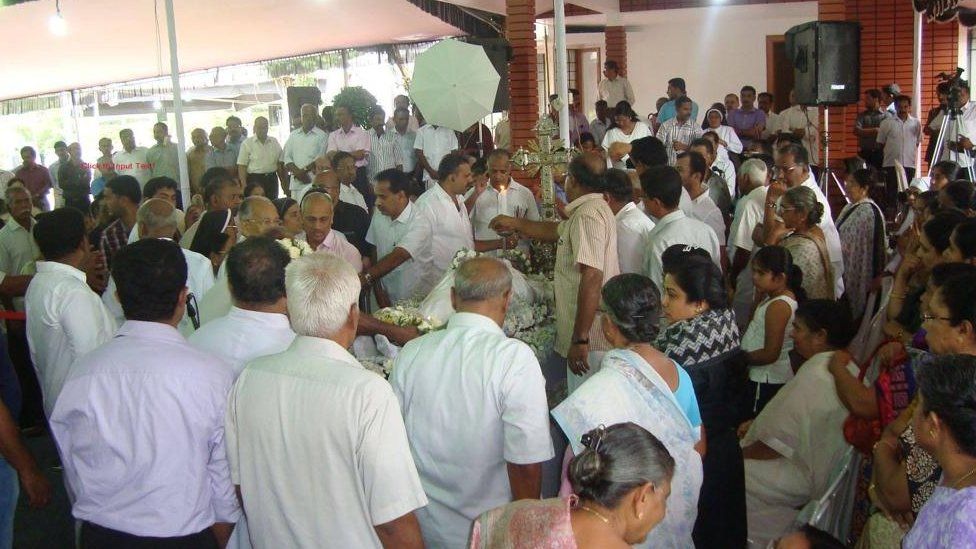 A crowd seen at a ritual outside a house