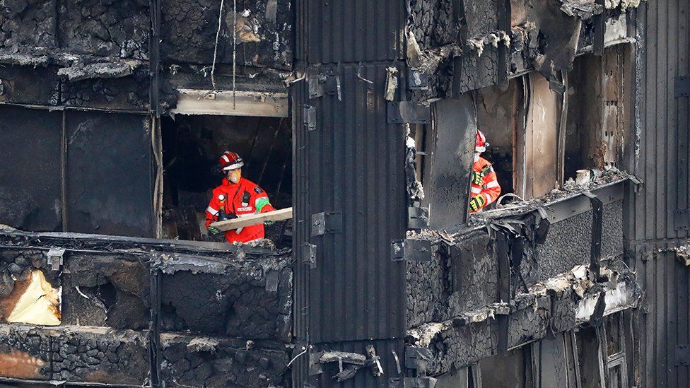 Members of the emergency services work on the middle floors of the charred remains of the Grenfell Tower block in 2017