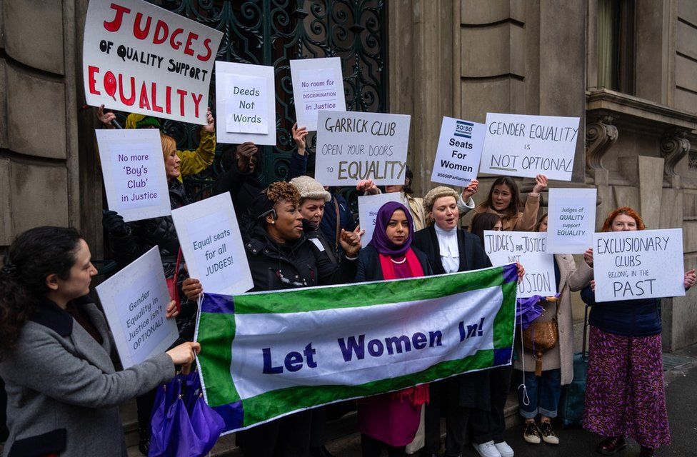 Female protesters holding signs outside the Garrick Club