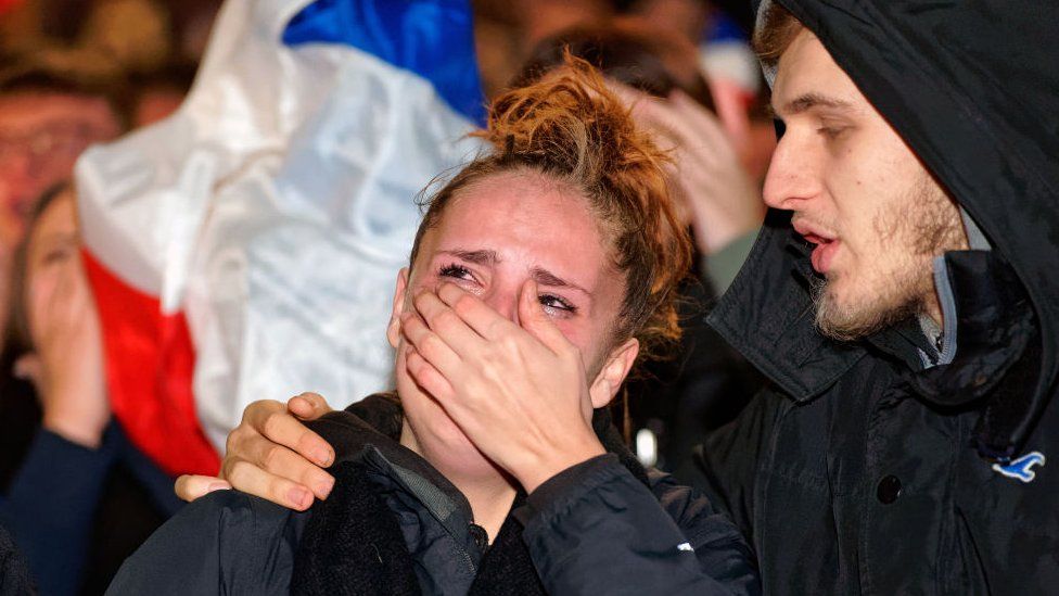 Мужчина утешает женщину после того, как Франция проиграла чемпионат мира по футболу