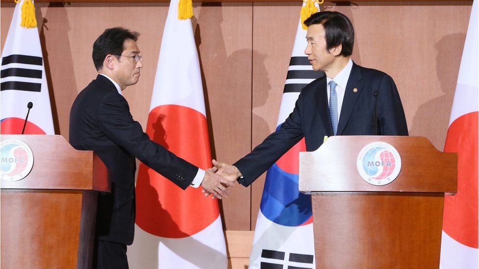 Japanese Foreign Minister Fumio Kishida (left) and South Korean counterpart Yun Byung-Se (right) shake hands during a joint press conference on 28 December