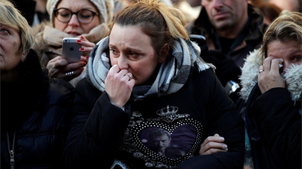 A woman cries as the coffin of the late French singer Johnny Hallyday arrives at the Madeleine church prior to the funeral ceremony in Paris, 9 December 2017