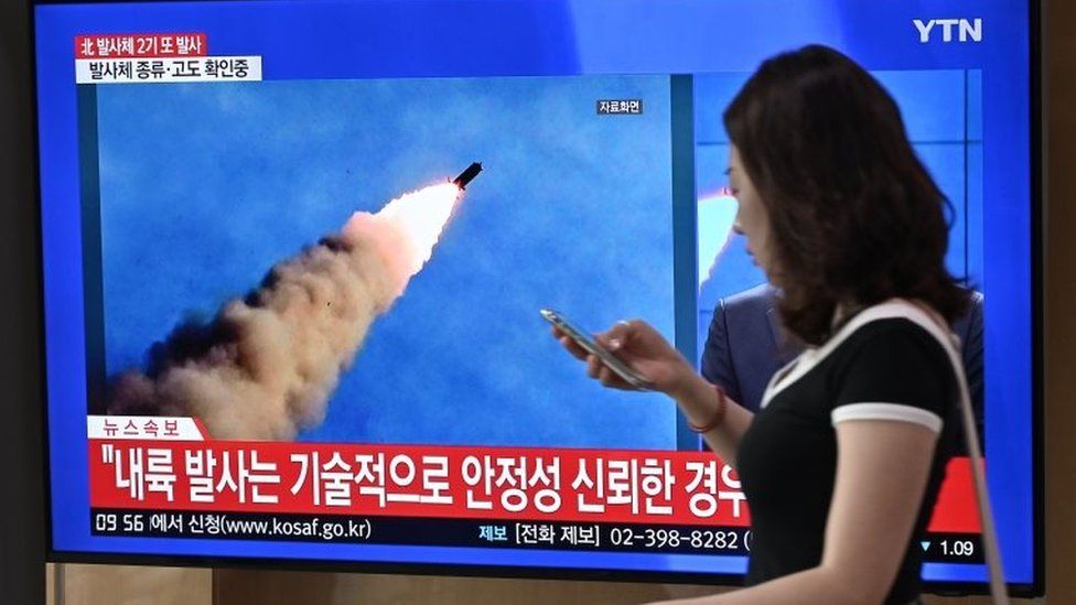 A woman walks past a television news screen showing file footage of a North Korean missile launch, at a railway station in Seoul on September 10, 2019.