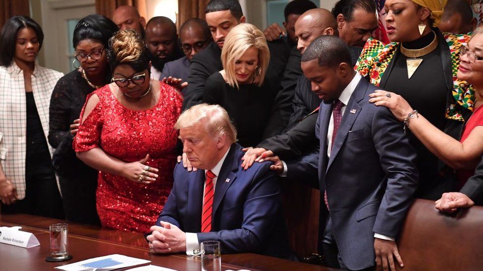 US President Donald Trump (C) stands in a prayer circle with African-American leaders