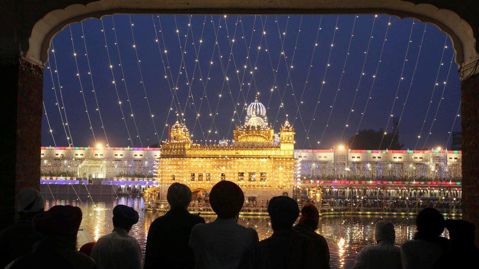 The Golden Temple lit up as Sikhs watch from a window