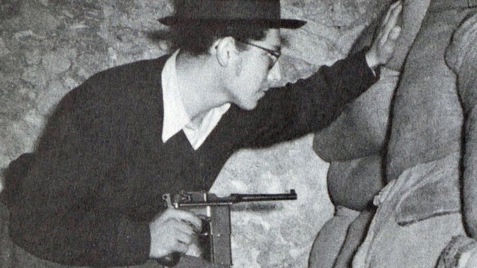 Haganah (Jewish Underground) fighter just before the start of the Israeli War of Independence 1948, wearing a hat and glasses, pointing a gun
