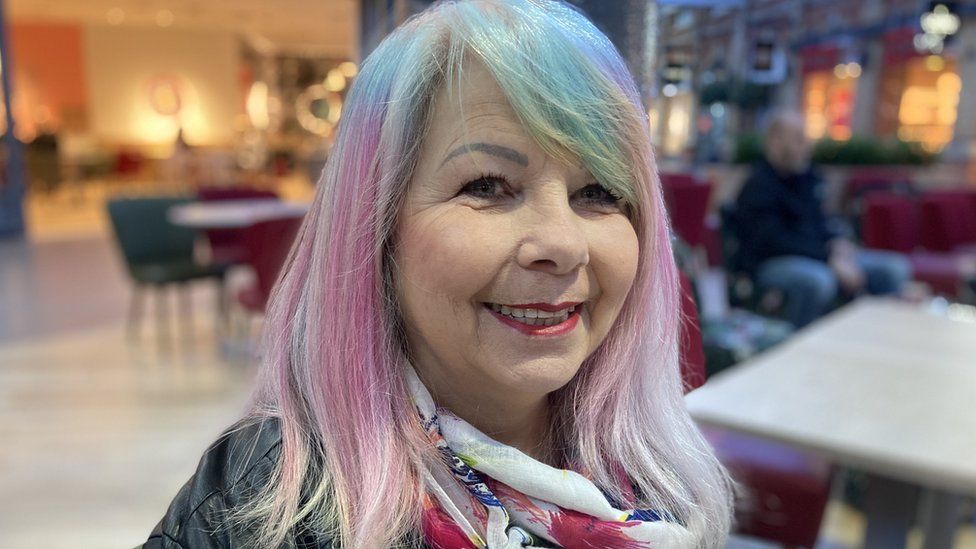 Carol with multi-coloured hair smiling at the camera